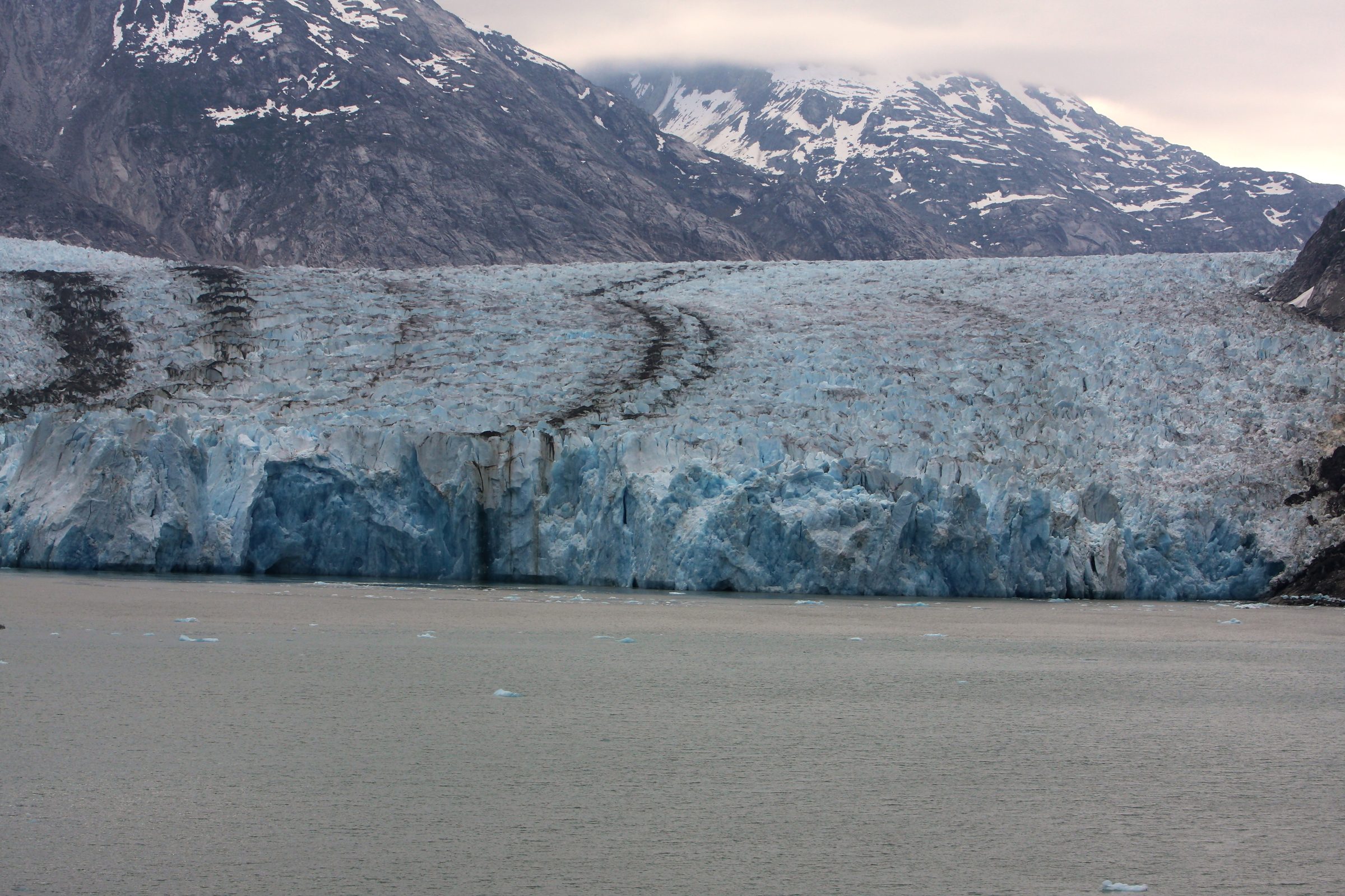Massive blue glacier face meeting grey glacial water.