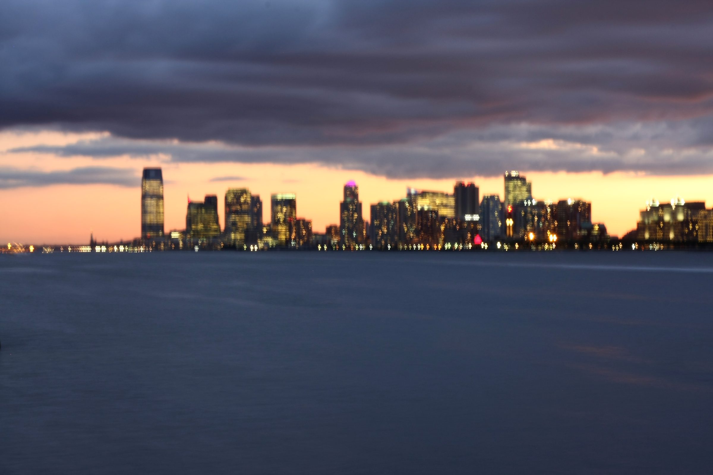City lights as soft bokeh across a twilight river.