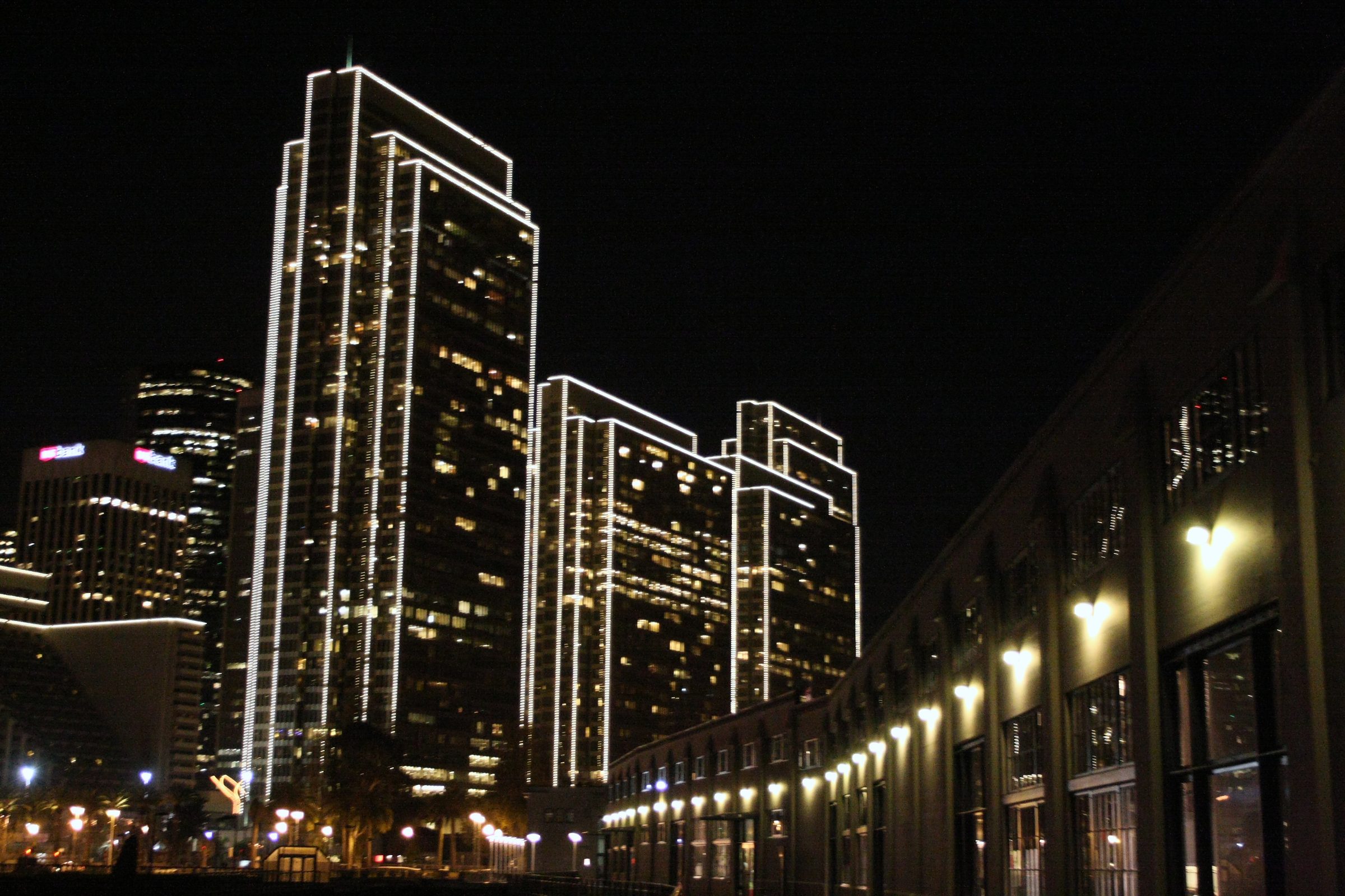 Modern high-rise outlined in white lights at night.