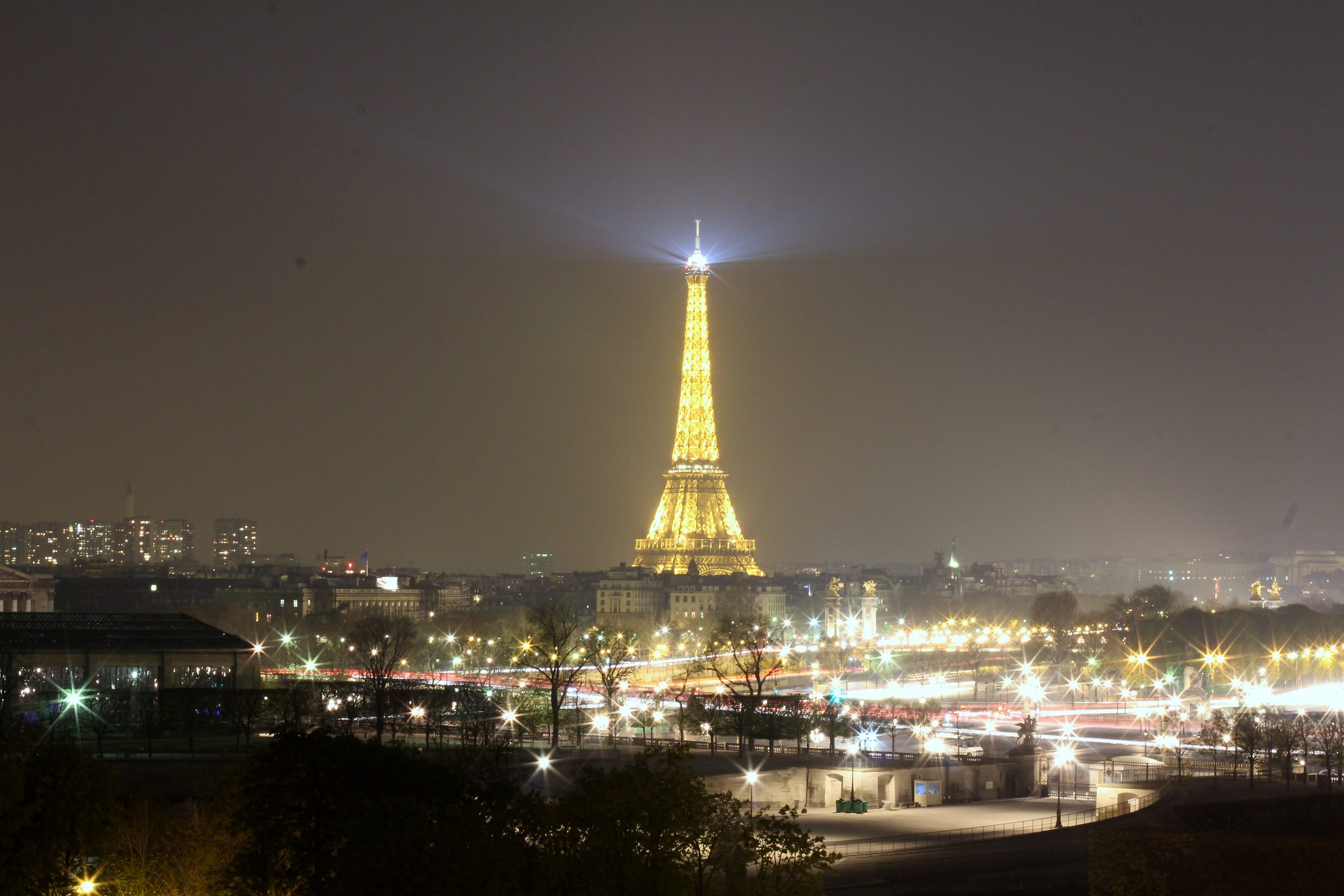Eiffel Tower glowing gold at night over Paris lights.