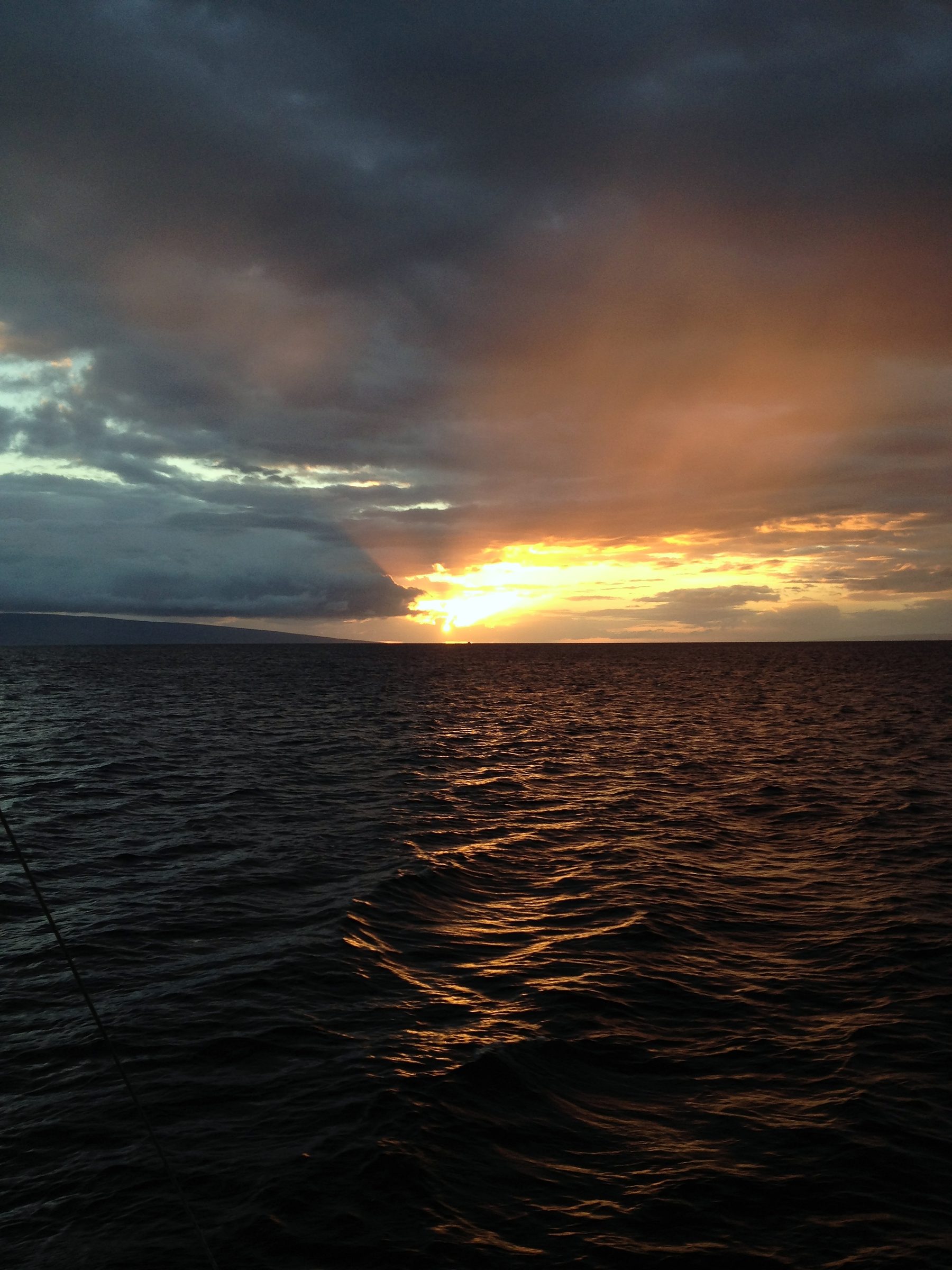 Moody ocean dusk with a copper slit of light through heavy cloud.