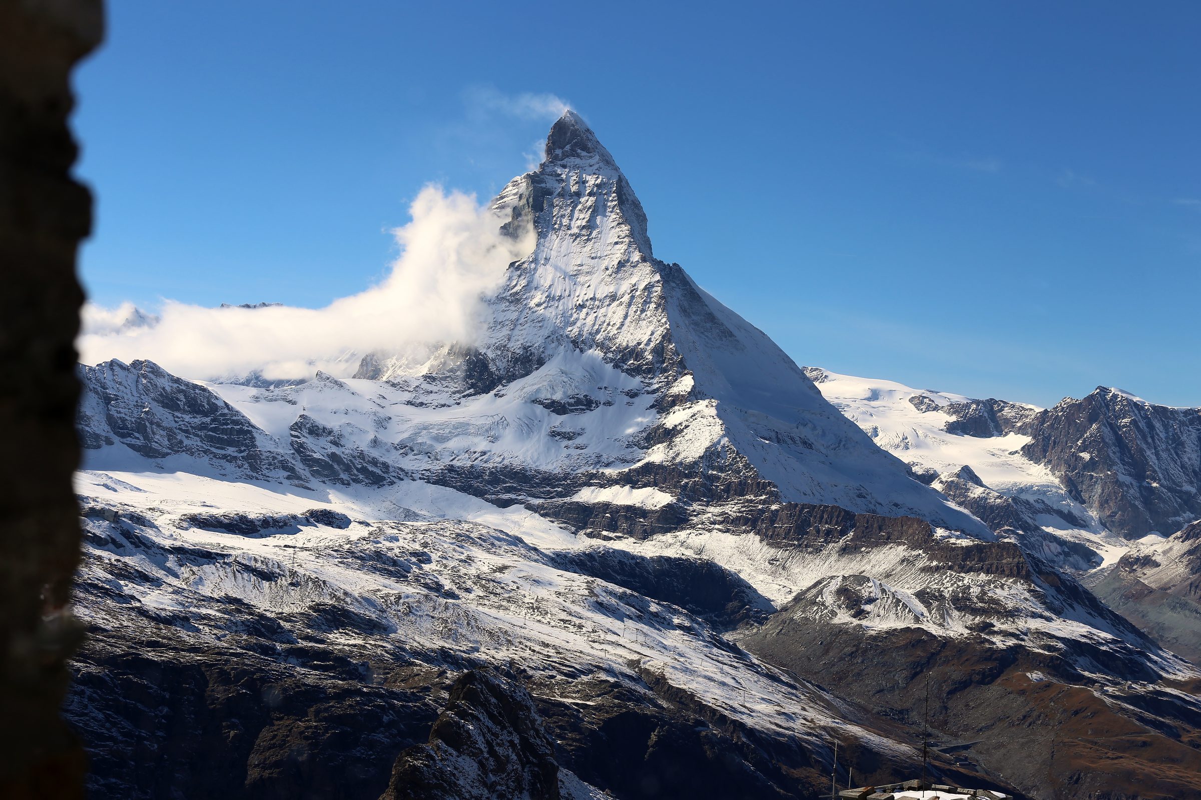 Matterhorn framed in a stone window with a hooked cloud on its shoulder.