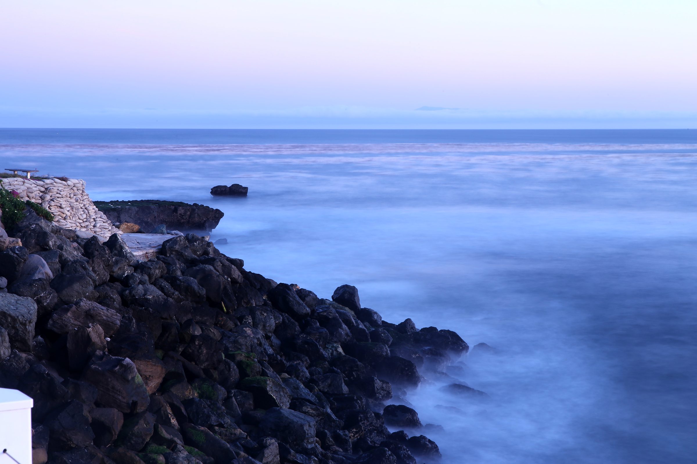 Twilight rocky overlook with sandbags and smoothed blue water.