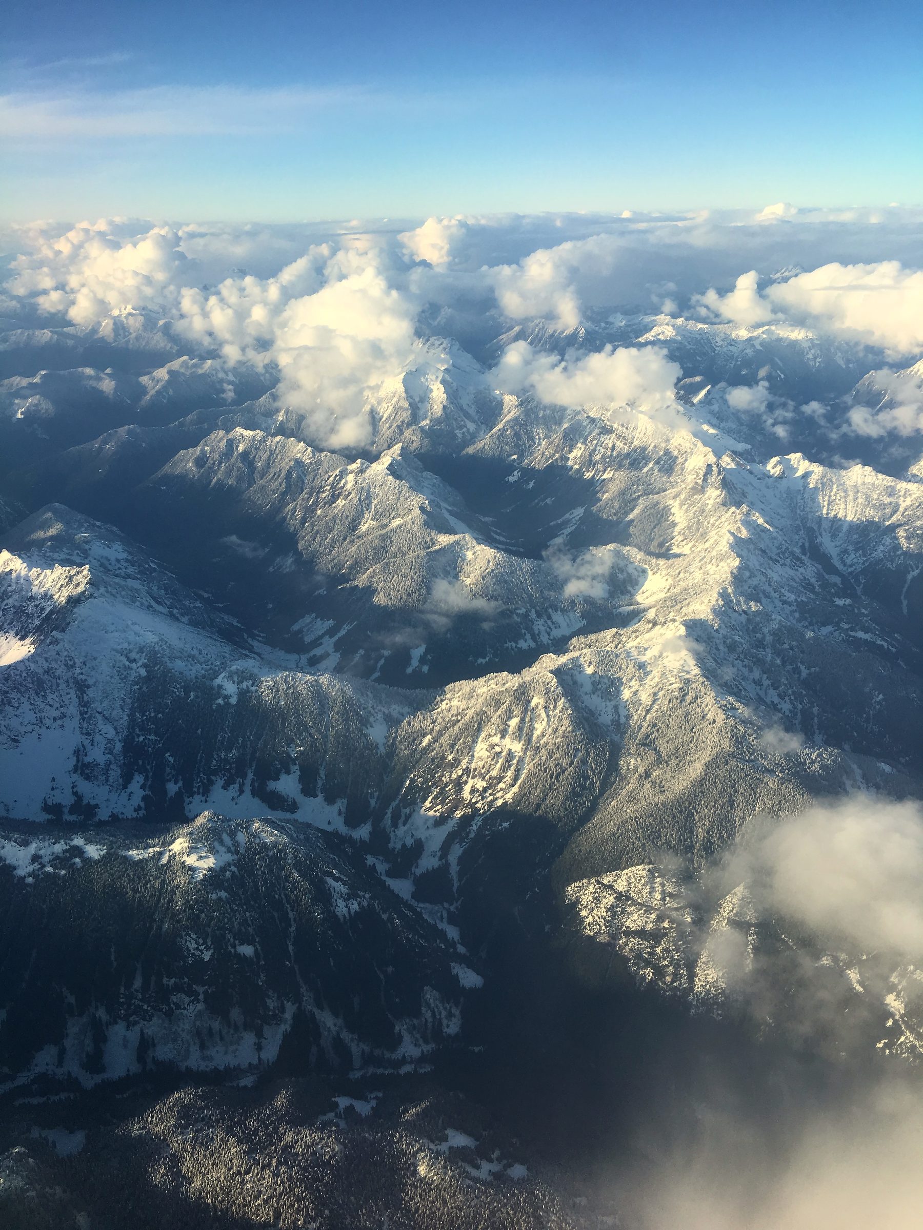 Bird's-eye labyrinth of snowy peaks and bright cloud light.