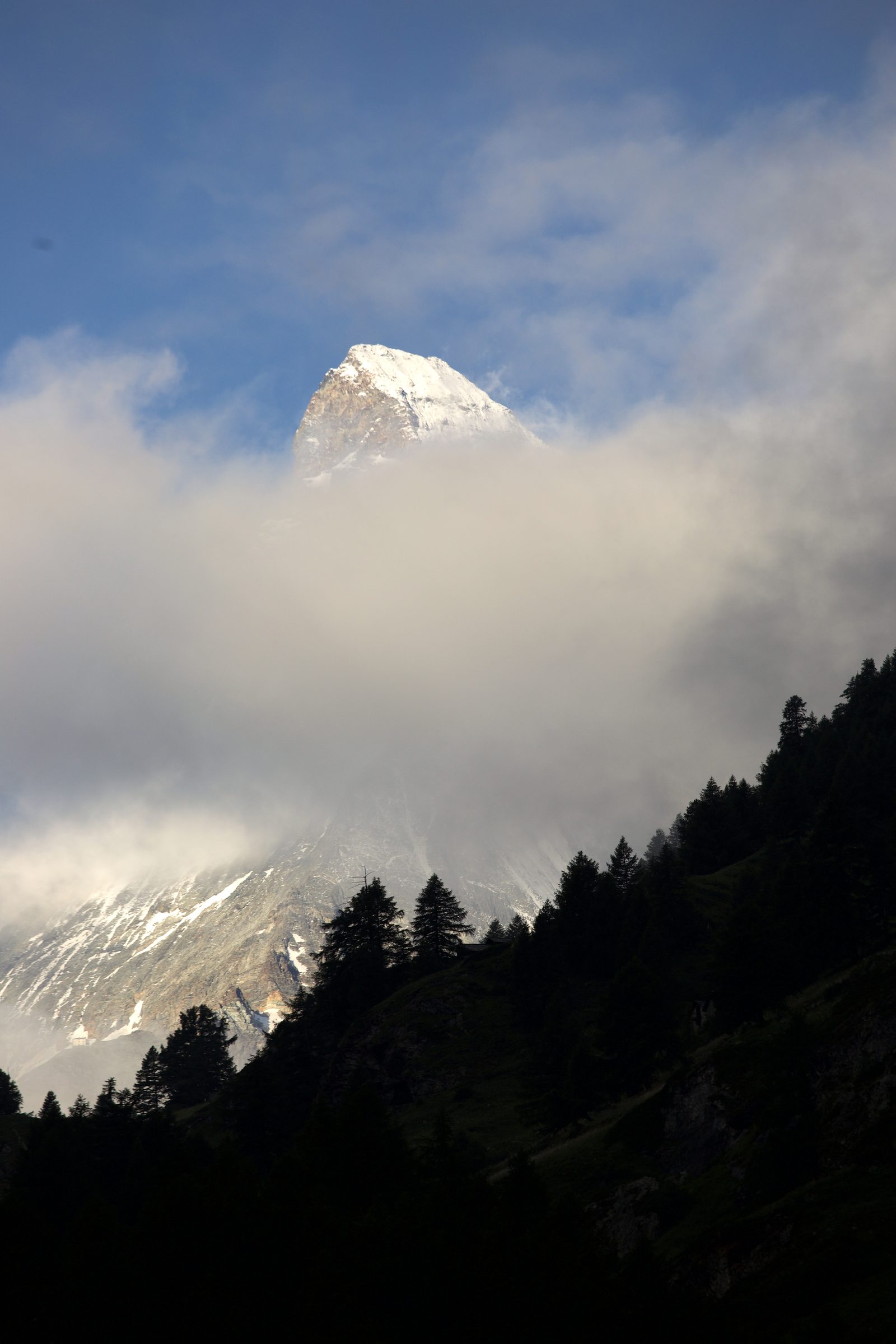 Snow peak emerging vertically above a thick cloud belt.