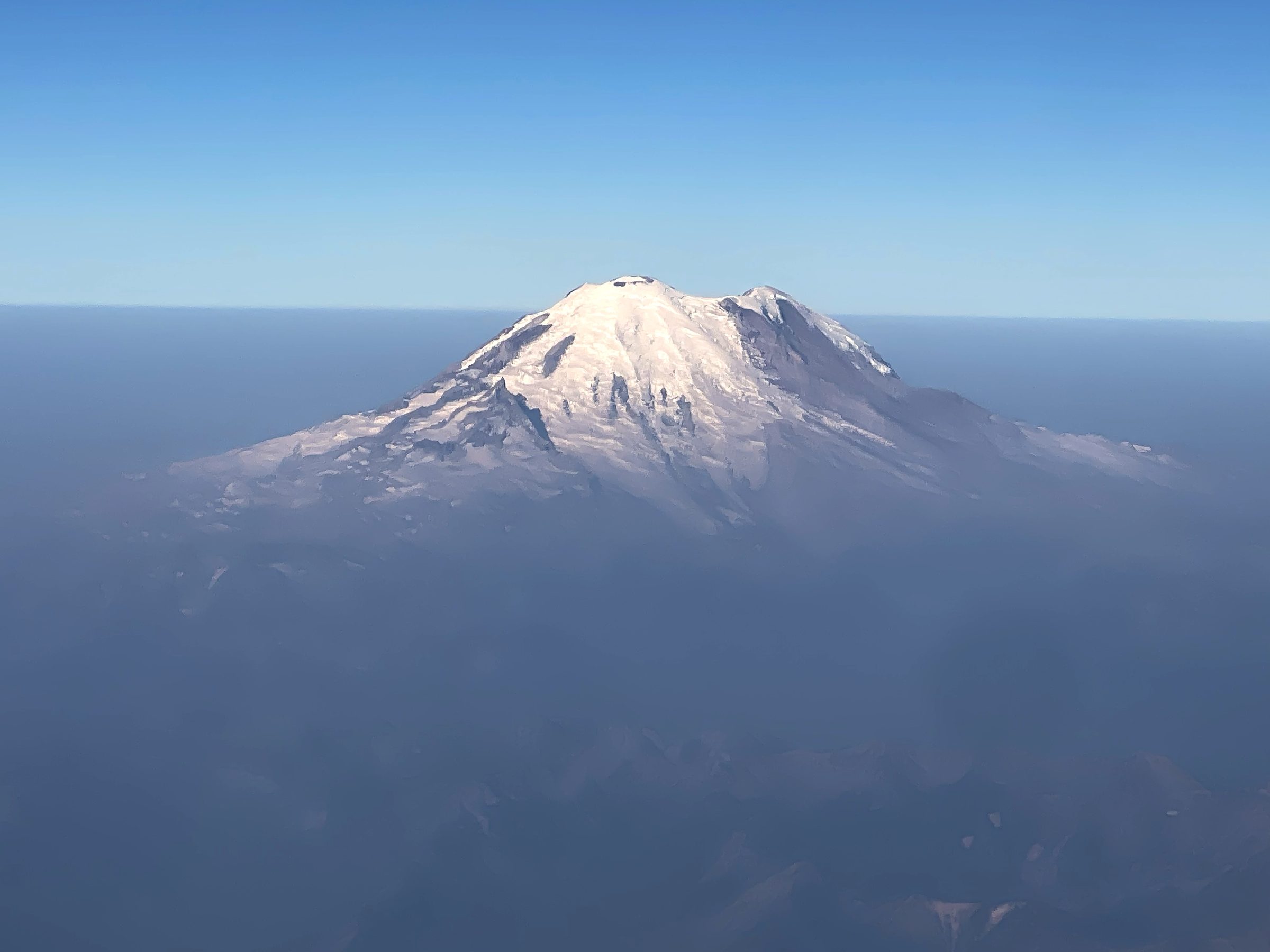 Isolated snow volcano peak floating in clear blue air.