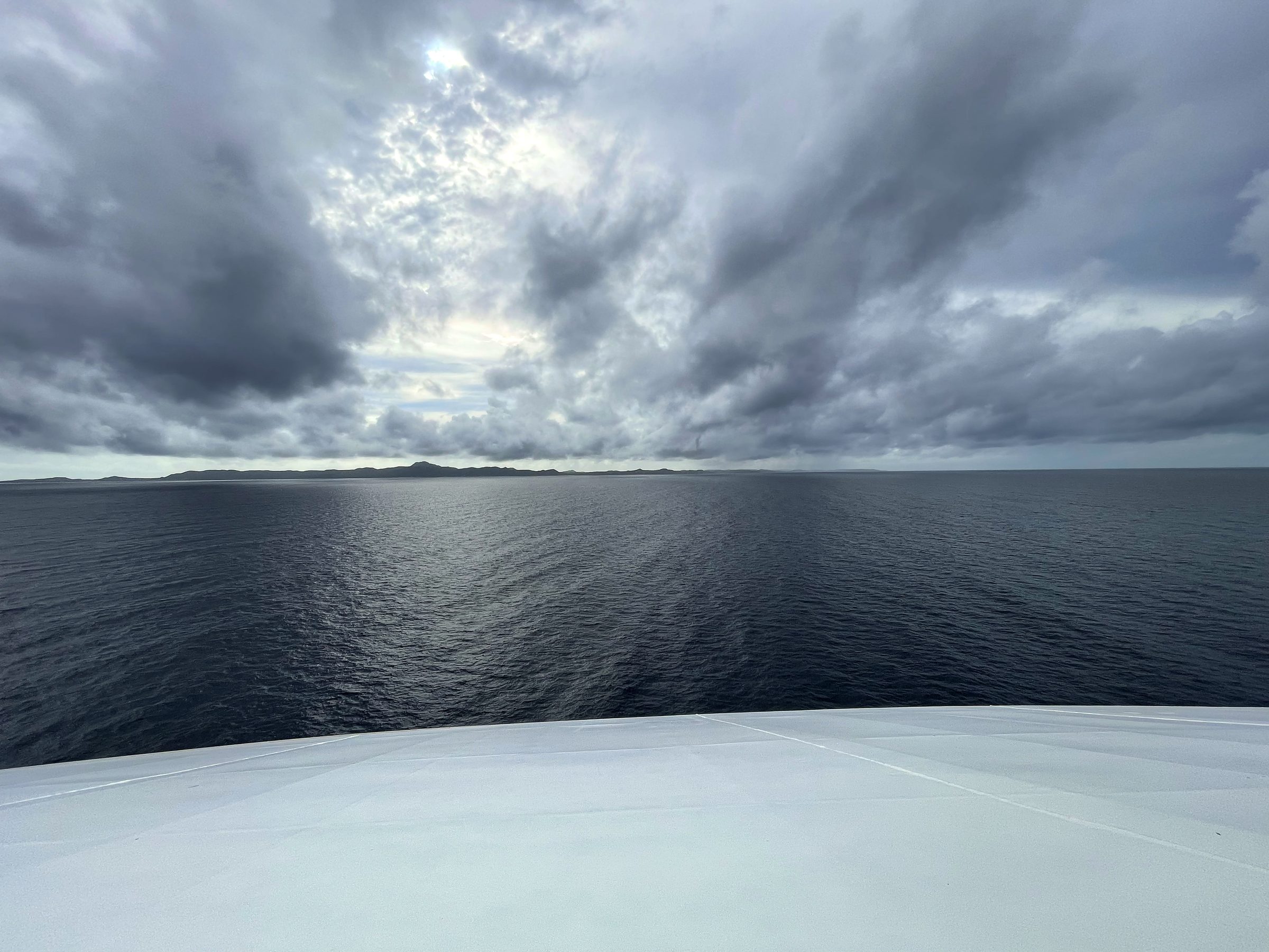 Curving deck view toward a dark stormy open coast.