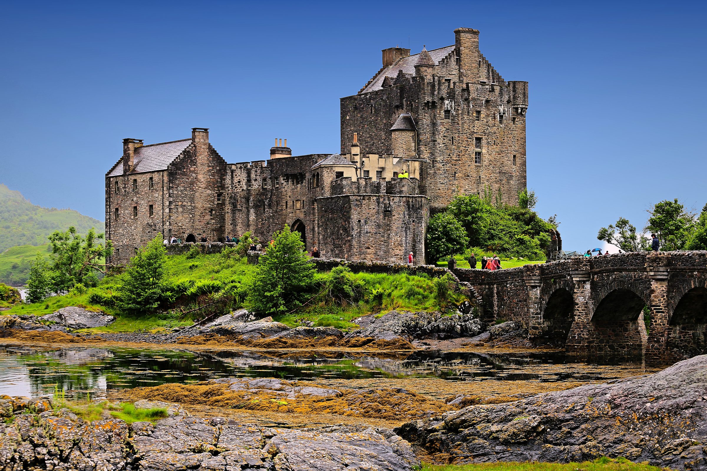 Stone castle on an island reached by an arched bridge.