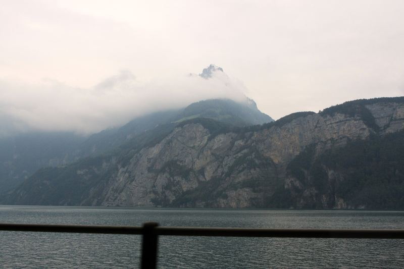 Metal railing overlooking a misty lake and rocky mountain.