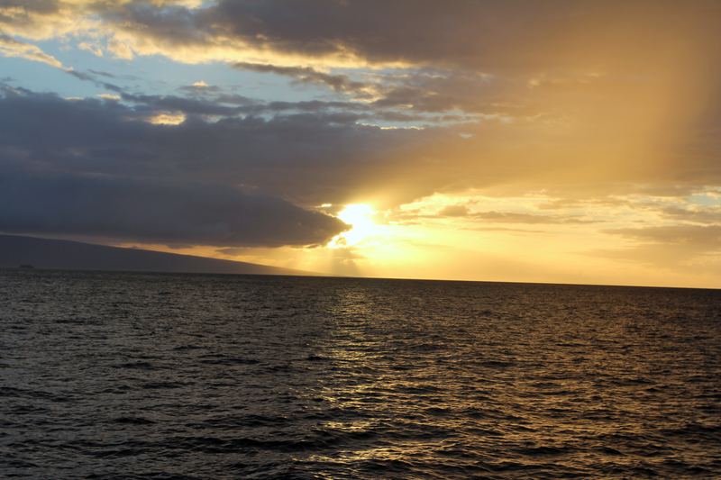 Sun rays breaking through heavy dark clouds onto the ocean.