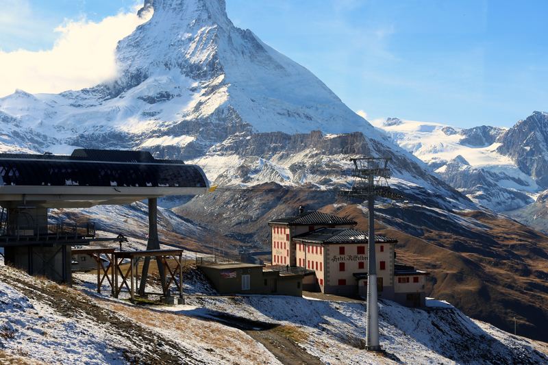 Alpine building with red shutters and ski lifts under the Matterhorn.