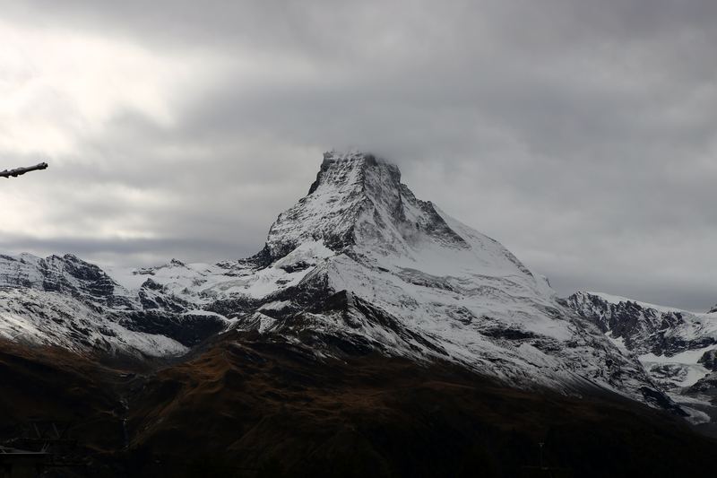 High-contrast Matterhorn peak under a heavy grey cloud lid.