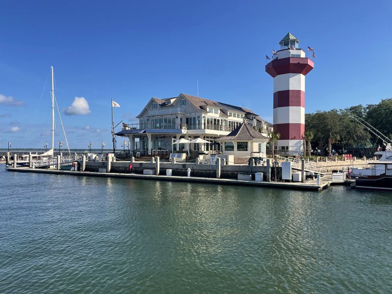 Red-and-white Harbour Town lighthouse beside marina buildings.