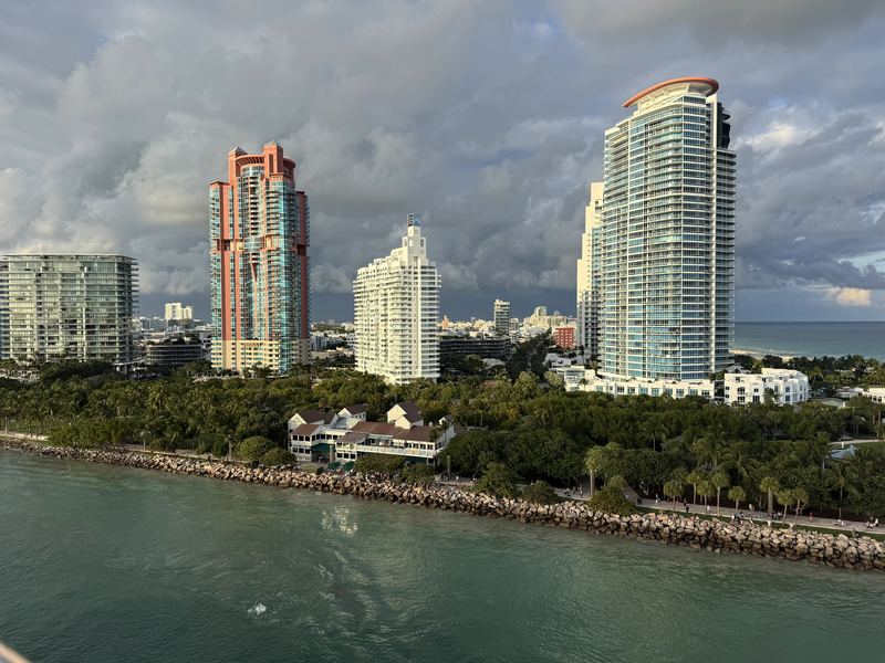 Miami high-rises behind a lush green park along turquoise water.